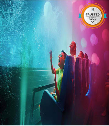 People in water-themed attraction with digital interactive wall display, blue and pink lighting effects